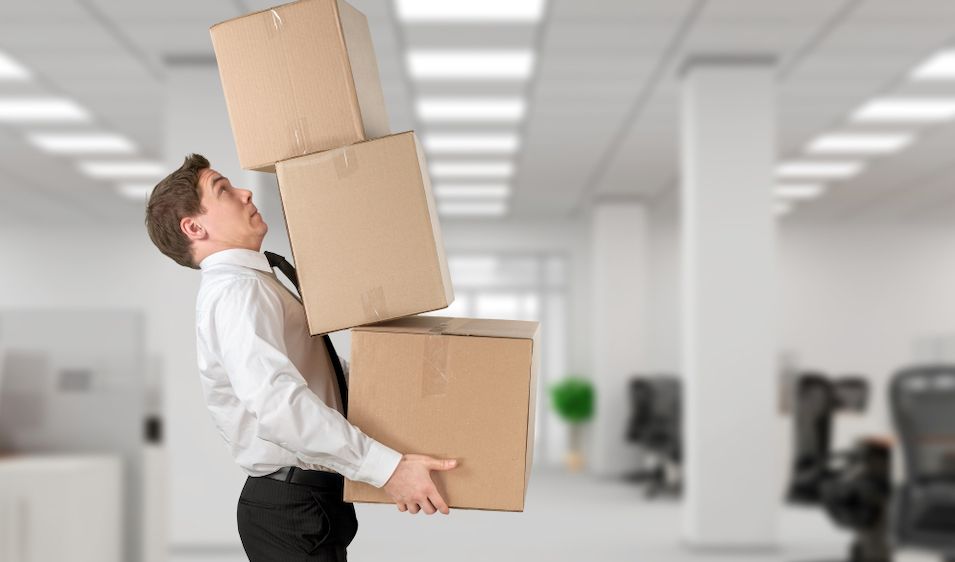 Young businessman juggling moving boxes in office
