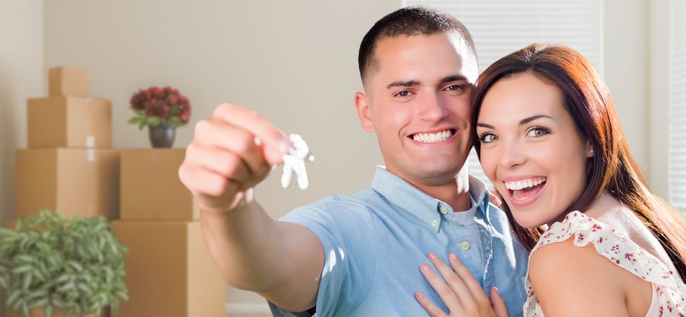 Young military couple holding keys in front of moving boxes