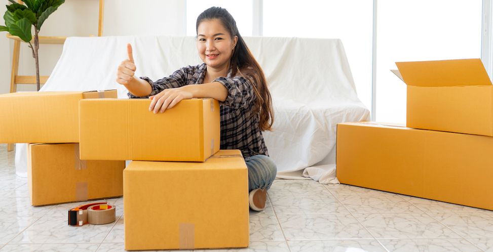 Asian woman smiling sitting behind moving boxes