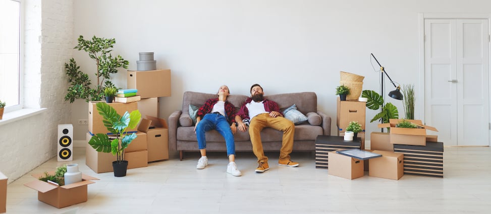 Young couple relaxing on couch surrounded by moving boxes