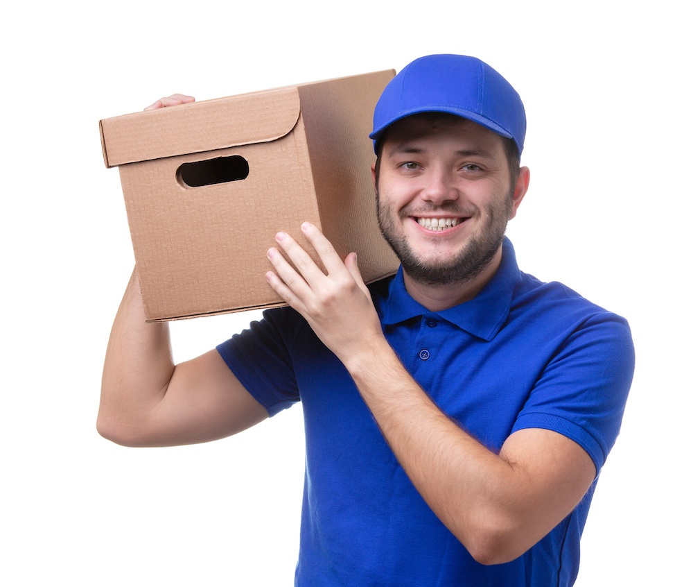 Picture of man in blue T-shirt and baseball cap with cardboard box on shoulder standing on white blank background